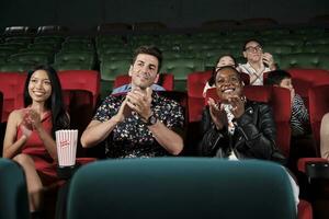 vários pessoas dentro teatro. multirracial audiências, Preto mulher, e amigos apreciar assistindo cinema e aplaudindo juntos em filme shows, entretenimento estilo de vida com filme, feliz e alegre sorri. foto