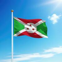 acenando bandeira do Burundi em mastro de bandeira com céu fundo. foto