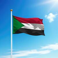 acenando bandeira do Sudão em mastro de bandeira com céu fundo. foto