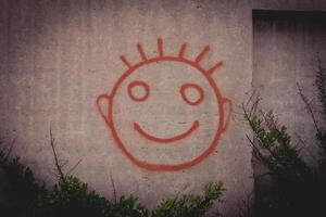 graffiti de uma carinha feliz vermelha em uma parede de concreto foto