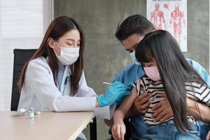 médica vacinando menina asiática na clínica de pediatria. foto