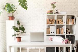 espaço de trabalho aconchegante e elegante com laptop, estantes e plantas
