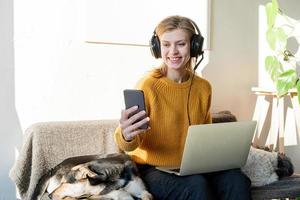 jovem sorridente com fones de ouvido pretos estudando on-line usando um laptop foto