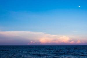 nuvens e lua no céu do pôr do sol sobre o mar foto