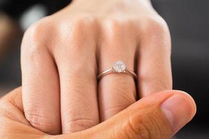 joias luxuosas de anel de diamante de noivado de mãos dadas foto