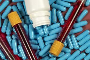 azul remédio cápsulas e branco garrafa e sangue teste tubo foto