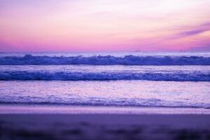 lindo pôr do sol às a de praia com surpreendente roxa pôr do sol vibrações. foto