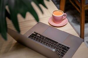 uma computador portátil em a mesa com uma copo do café. foto