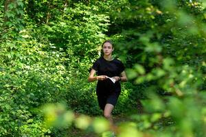 jovem menina dentro floresta lendo mapa e procurando para uma ao controle ponto. Esportes orientação concorrência. foto