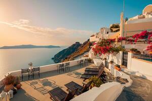 arquitetura branca na ilha de santorini, grécia. restaurante ao ar livre sob uma fantástica paisagem por do sol, cadeiras para casal. vista do pôr do sol romântico, céu laranja e nuvens. férias de verão, viagens de lua de mel foto