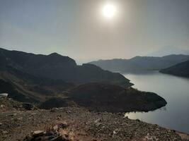 uma lindo dia Visão do wadi qanuna barragem dentro al bahá, saudita arábia. a água do a barragem e a em torno da colinas estão apresentando uma lindo cena dentro a luz solar. foto