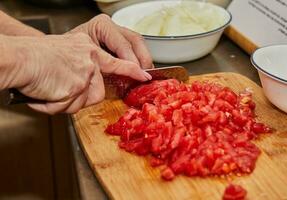 chefe de cozinha cortes a tomates para dentro pequeno cubos para cozinhando foto