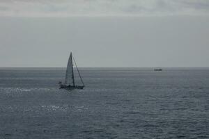 barco a vela com vela desenrolado, Navegando em a calma mar às pôr do sol. foto