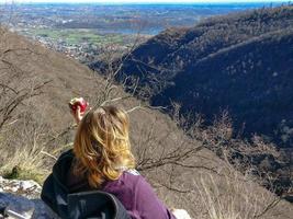 mulher com cabelo loiro descansando comendo uma maçã no topo de uma montanha
