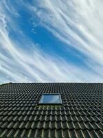 janela de telhado aberta em estilo velux com telhas pretas. foto