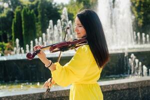 mulher artista com Sombrio cabelo dentro uma vestir tocam uma de madeira show elétrico violino foto