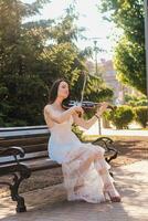 mulher artista com Sombrio cabelo dentro uma vestir tocam uma de madeira show elétrico violino foto