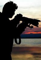 silhueta de um fotógrafo perto da beira-mar foto