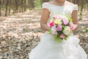 noiva segurando um grande buquê de casamento na floresta. foto