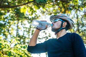 os ciclistas ficam no topo da montanha e bebem uma garrafa de água. foto