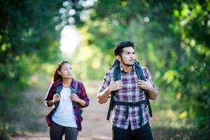 jovem casal andando com mochilas na floresta. caminhadas de aventura. foto