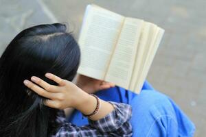 feliz atento jovem ásia mulher Faculdade aluna lendo uma livro dentro a parque, Educação conceito foto