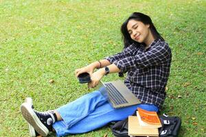 animado lindo ásia aluna usando computador portátil e Smartphone e lendo livro para estudando e planejamento dela trabalhos foto
