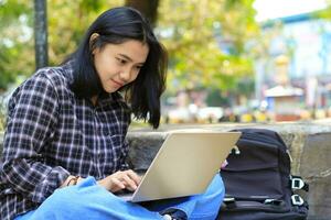 relaxar ásia jovem mulher sorridente usando computador portátil trabalhando freelance e feliz pegue e comércio oferta foto