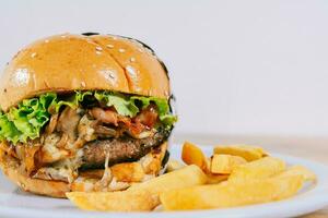 grande Hamburguer de queijo com fritas servido com cópia de espaço. caseiro hamburguer com francês fritas em uma prato em de madeira mesa foto