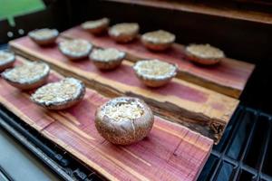 Grelhando cogumelos portobello em uma prancha de cedro foto