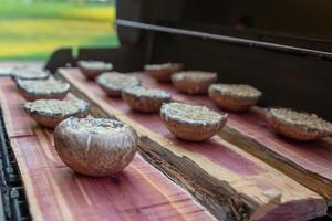 Grelhando cogumelos portobello em uma prancha de cedro foto