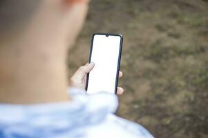 fechar acima do uma homem com célula telefone dentro mão, fechar acima tiro do uma pessoa verificação dele célula telefone, jovem cara com célula telefone dentro mão com cópia de espaço foto