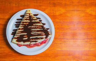 Tapioca com chocolate creme e morango em de madeira mesa. doce morango Tapioca com chocolate creme em de madeira mesa foto