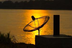 antena parabólica no reflexo do rio no fundo do sol