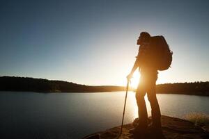 silhueta de homem alpinista com mochila na montanha de paisagem do sol. foto