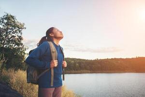 mulher jovem caminhante em pé sobre a rocha e apreciando o pôr do sol sobre o lago. foto