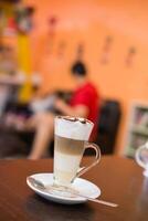 xícara de café com padrão de lóbulo de flor em revelar xícara na mesa de madeira. foto