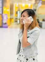 bela jovem fala por um telefone móvel em shopping center. foto