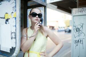 jovem mulher em pé conversando em uma público telefone foto