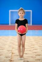 pequeno ginasta menina com vermelho bola foto