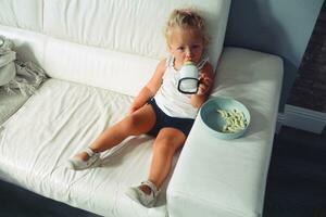 menina criança pequena tendo uma lanche às casa foto