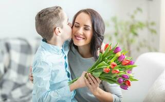 jovem mãe recebendo uma ramalhete cheio do tulipas a partir de dele filho durante nacional mulheres dia foto