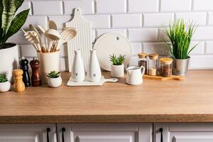 branco cerâmico utensílios e cozinha utensílios em uma de madeira bancada dentro a ecológico cozinha com verde interior plantas. acolhedor casa foto