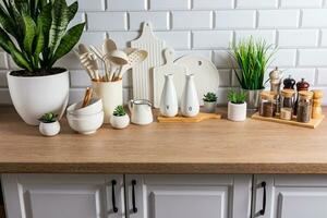 lindo cozinha fundo do uma moderno bancada com uma conjunto do vários cozinha utensílios, verde plantas dentro potes. eco estilo. natural materiais. foto