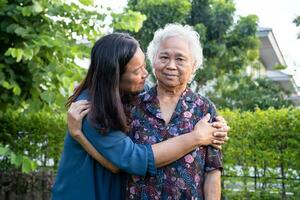 ásia idosos mulher abraço com dela filha com amor, Cuidado, ajuda, encorajar e empatia às parque, saudável Forte médico conceito. foto