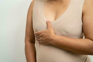 paciente mulher asiática verificando e preocupando seu peito, auto-exame de mama ou bes, símbolo do dia mundial do câncer de mama. foto