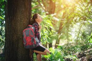 mulher caminhante cansada relaxa com uma grande caminhada de mochila na floresta. foto