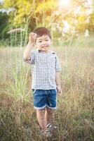 menino asiático feliz brincando ao ar livre. bonito rapaz asiático em campo. foto