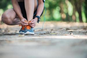 jovem fitness mulher sentada amarrar os sapatos antes de ir correr. foto
