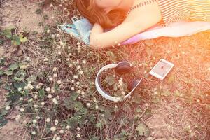 vista superior de uma jovem deitada perto de um fone de ouvido no campo de flores foto